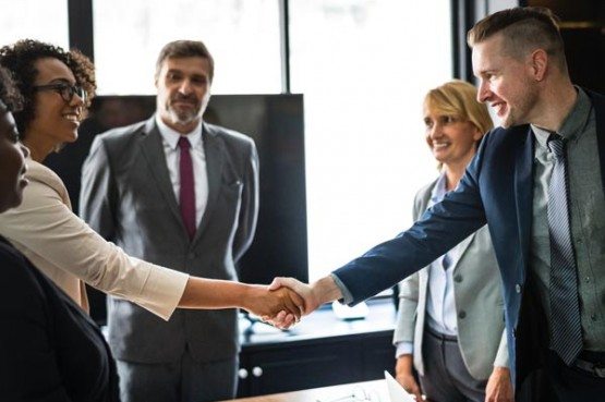 a business meeting of four people smiling and shaking hands